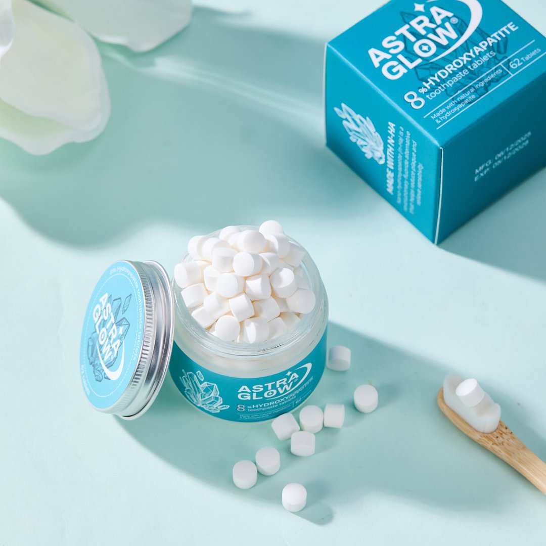 Hydroxyapatite toothpaste tablets in a glass jar with a toothbrush and product box